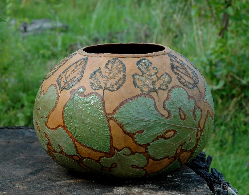 Gourd bowl with white mulberry leaves attached to the exterior surface.